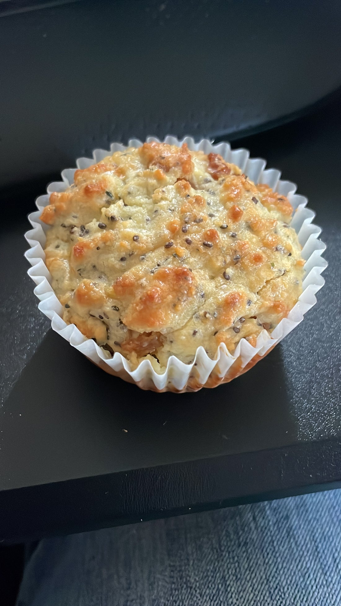 a golden brown no-bran muffin with raisins, hemp and chia seeds, in a paper muffin cup