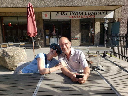 Siri Bhandu and Greg Brooks sitting at a table at an outdoor cafe.